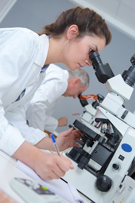 woman looking into a microscope doing independent testing